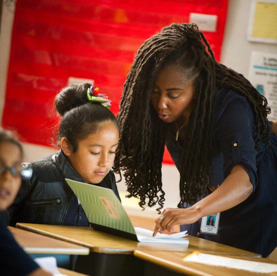 Female teacher instructing young student.