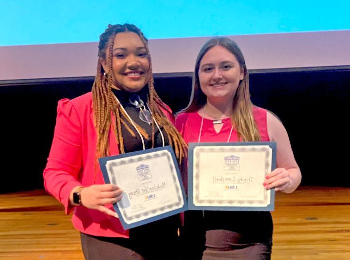 Two students pose side-by-side with their award certificates.