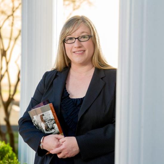 A person in professional attire holding books.